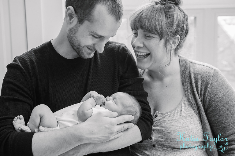 Toronto Newborn Portrait. Mother and father laugh with newborn baby