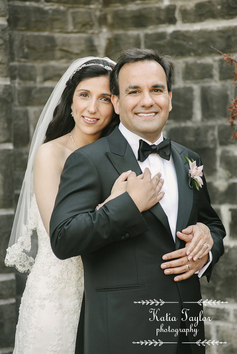 Bride and groom pose by stone wall