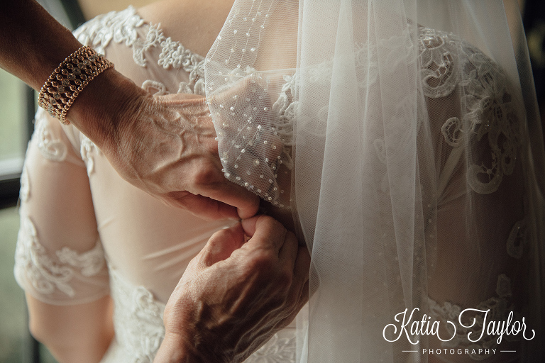 Close up of bridesmaid helping the bride do up her wedding gown. The Old Mill in Toronto.