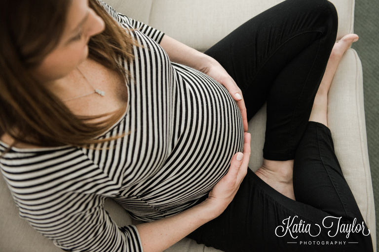 Overhead angle of pregnant woman sitting on the couch. Toronto lifestyle maternity portraits. 