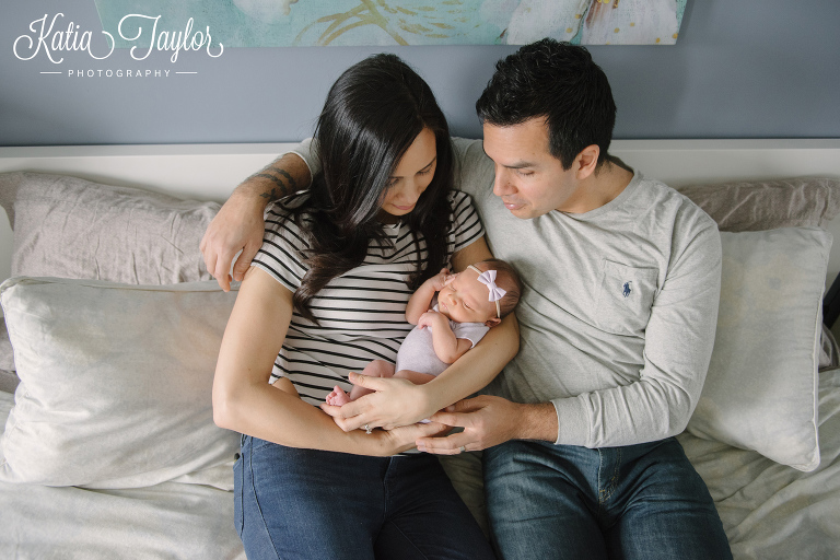 Couple on the bed with their newborn baby girl. Toronto newborn photographer. www.katiataylorphotography.com