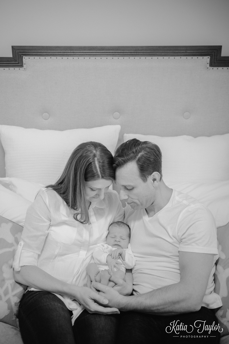 Mother and father hold their newborn baby in bed. Toronto lifestyle newborn photos. www.katiataylorphotography.com