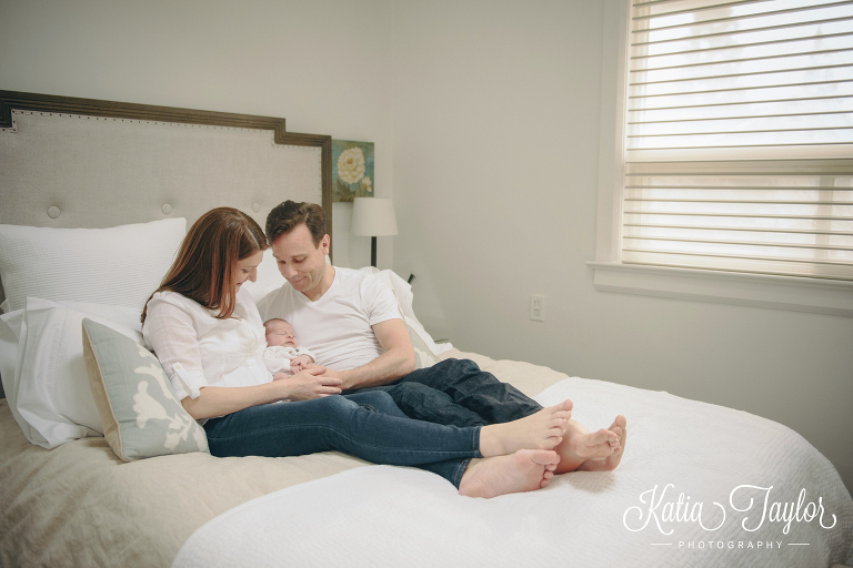 New parents cuddle their baby boy on the bed. Toronto lifestyle newborn photos. www.katiataylorphotography.com