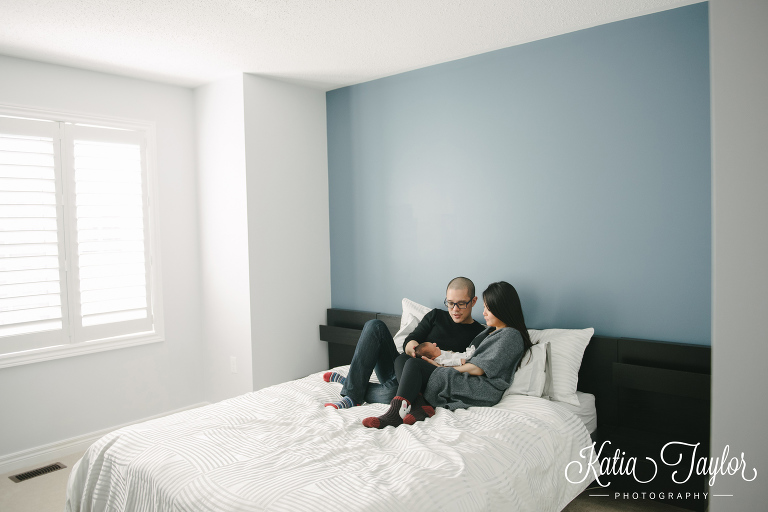 New parents cuddle with baby boy on the bed. Toronto newborn photography.