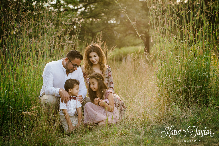 Family sitting in tall grass at sunset. Toronto family portraits in High Park. 