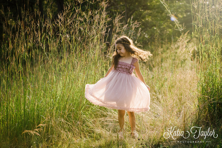 Little girl spinning around in the tall grass at sunset. Toronto family portraits in High Park. 