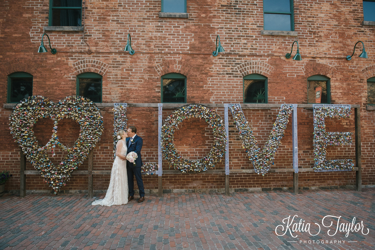 Bride and groom kiss by the LOVE lock wall. Toronto Distillery District Wedding, Archeo Restaurant Wedding.