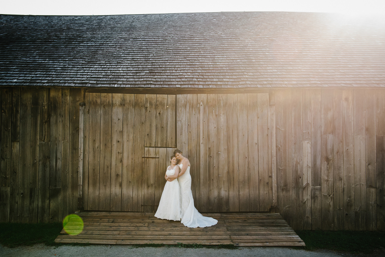 Sun-drenched portrait of lesbian brides. Toronto same-sex wedding. Black Creek Pioneer Wedding.