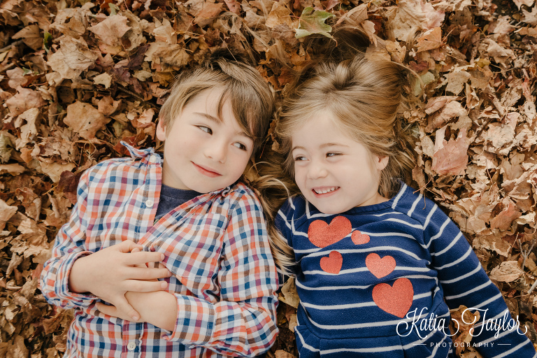 Brother and sister lying in Fall leave. Toronto High Park Fall family portraits.