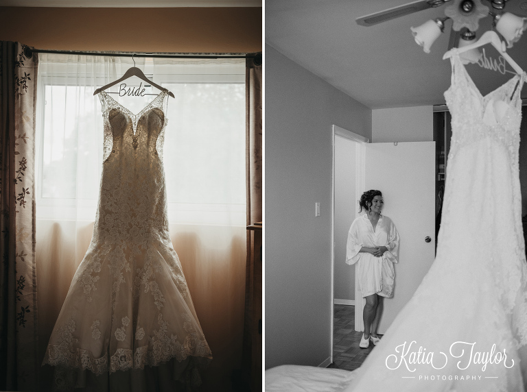 Wedding gown hanging in window as bride looks on. Toronto Ontario wedding photography.