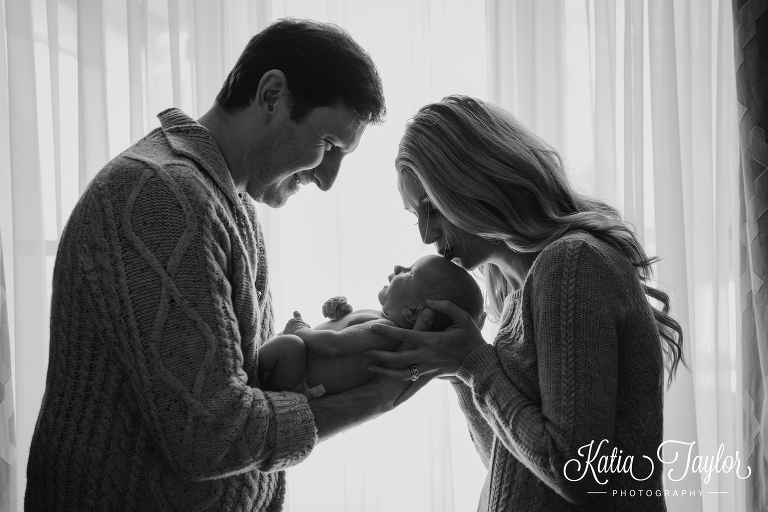 New parents with their baby boy in the window light. Toronto newborn photos.