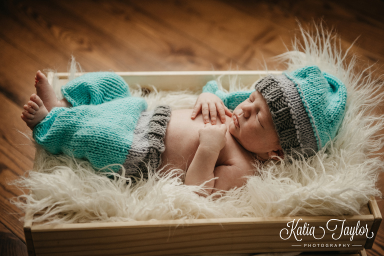 Sleeping newborn boy in a matching knit pants and hat. Toronto newborn baby photographer.