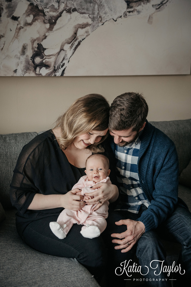 Parents snuggling their smiley baby girl. Two-month-old baby girl. Toronto baby photos.