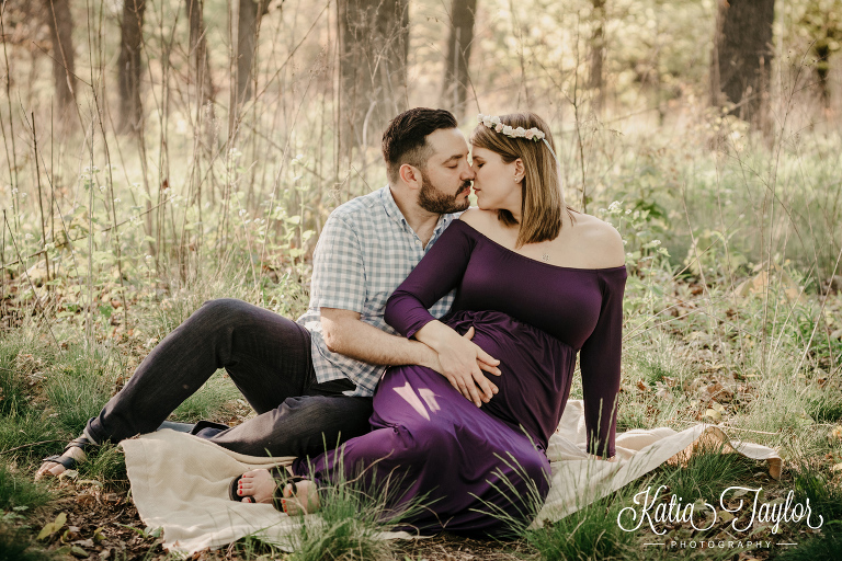 Couple sitting on a blanket in the forest. Maternity photos in nature. Flower crown. Toronto High Park Maternity Portraits.