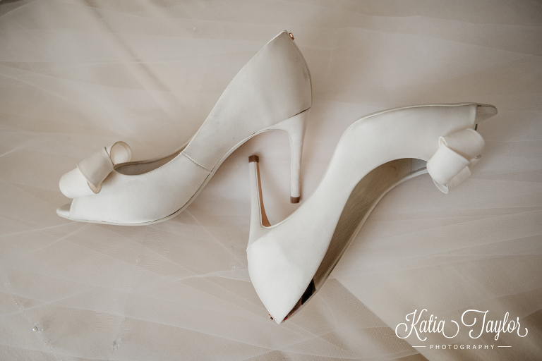 White satin bridal shoes on top of bride's veil. Toronto wedding photography.