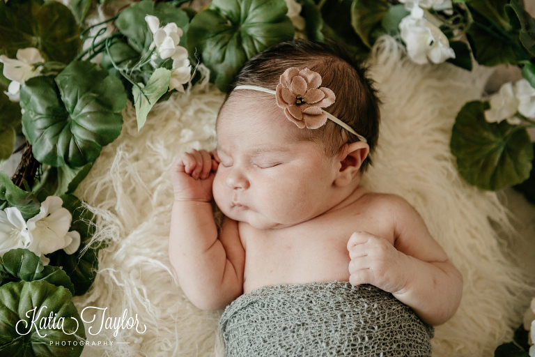 Newborn baby girl sleeping surrounded by a flower wreath. Toronto newborn photography.