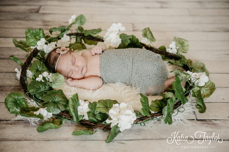 Newborn baby girl sleeping on a fur rug surrounded by a flower wreath. Toronto newborn photography.