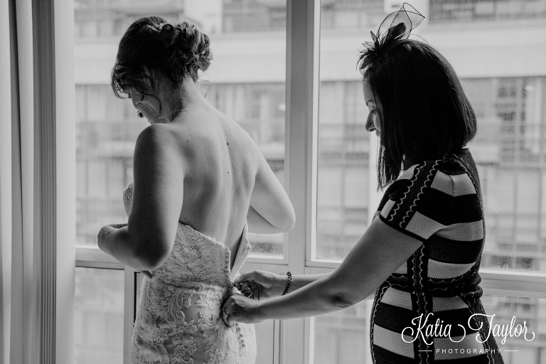 Maid of honor doing up the brides wedding dress. Toronto wedding photography.