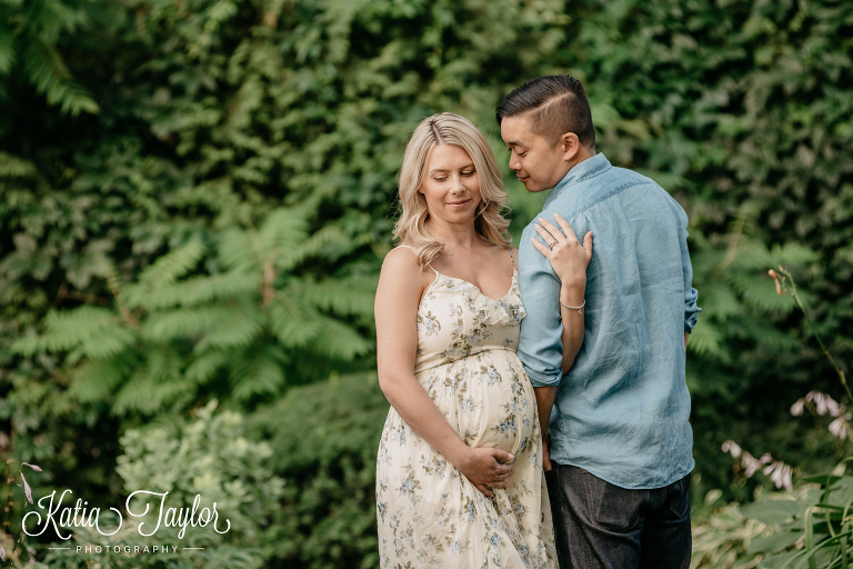 Pregnant woman and her partner in a lush garden in the summertime. Toronto maternity photography.