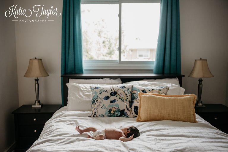 Tiny newborn baby asleep in the bed in the master bedroom. Toronto newborn portraits.