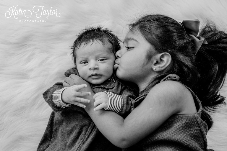 Big sister kisses her newborn baby brother.