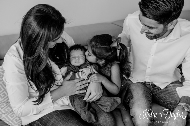 Big sister kisses her baby bother as parents watch.