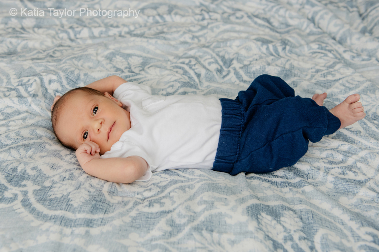 Cute newborn baby boy lying on the bed smiling at the camera