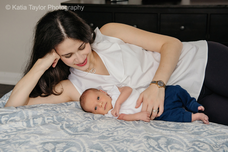 Mother lying with her newborn baby boy on the bed