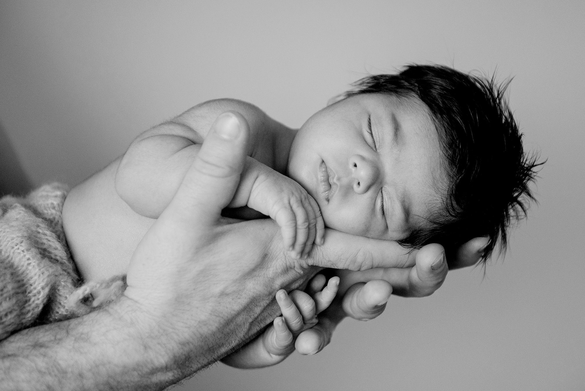 Newborn baby girl asleep in her father's hands